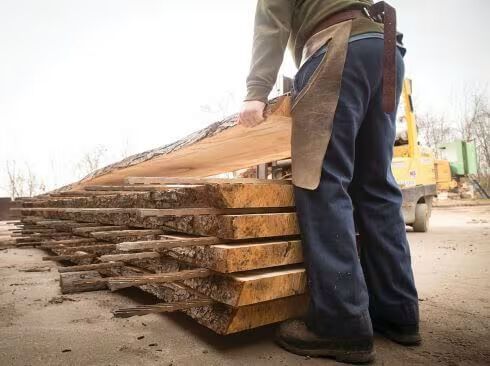 artisan handling slab on a stack of lumber