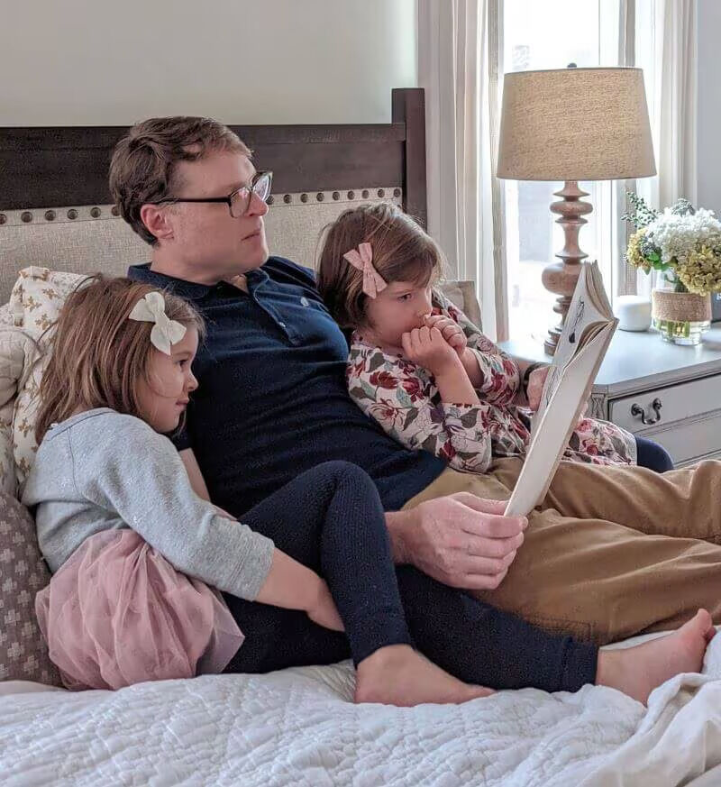 Julia's husband reading to daughters in bed
