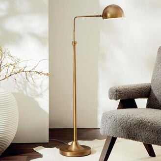 Floor lamp beside accent chair with standing mirror leaning against background wall