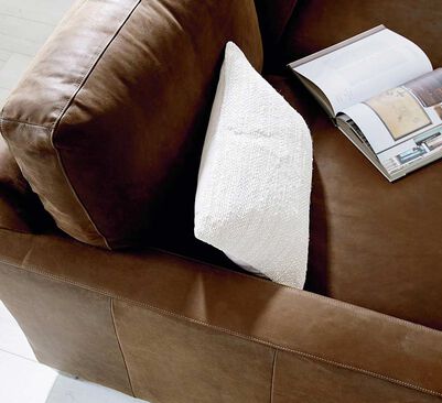 Accent pillow & book on top of brown leather sofa