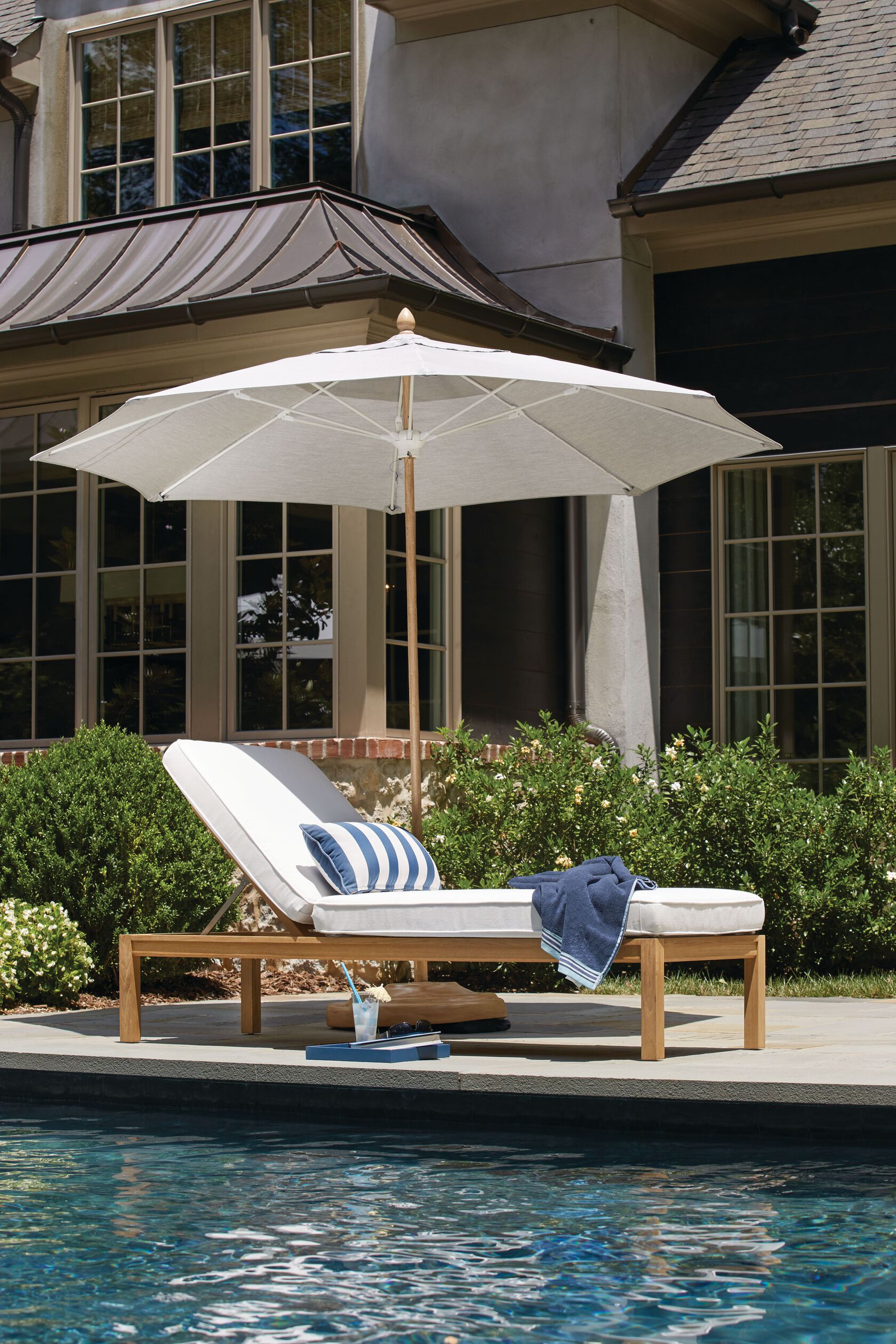 chaise under an umbrella by a pool