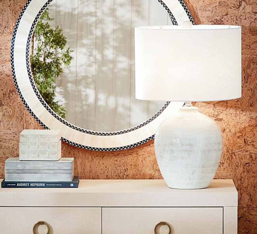Console table with lamp, book decor and a mirror hanging on wall above