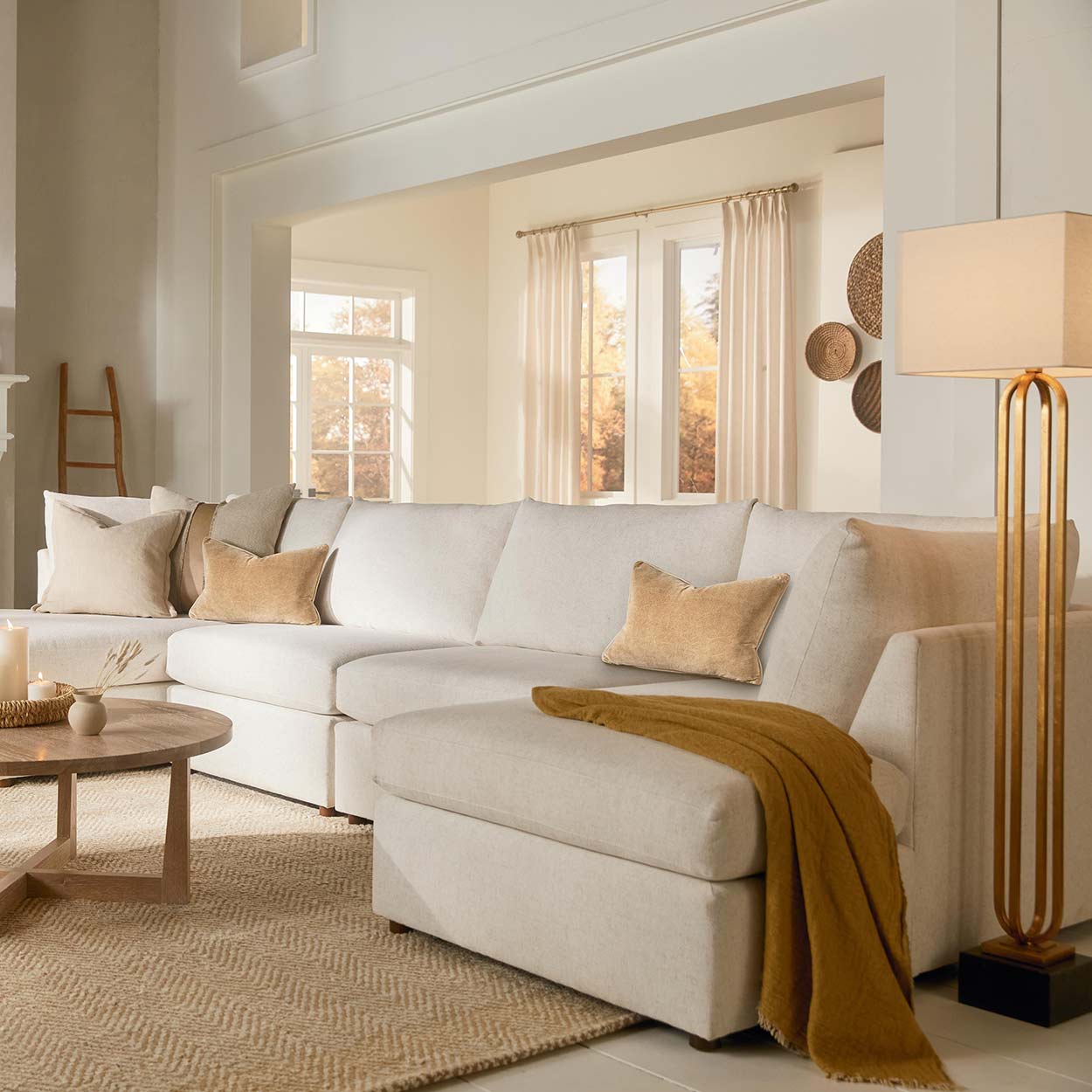 Neutral sectional sofa with throw pillows in a bright living room beside a wood side table and coffee table.